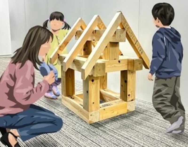 神奈川県産の木材で組み立てた小さなおうちの模型を囲んで、親子が家づくりを体験している様子